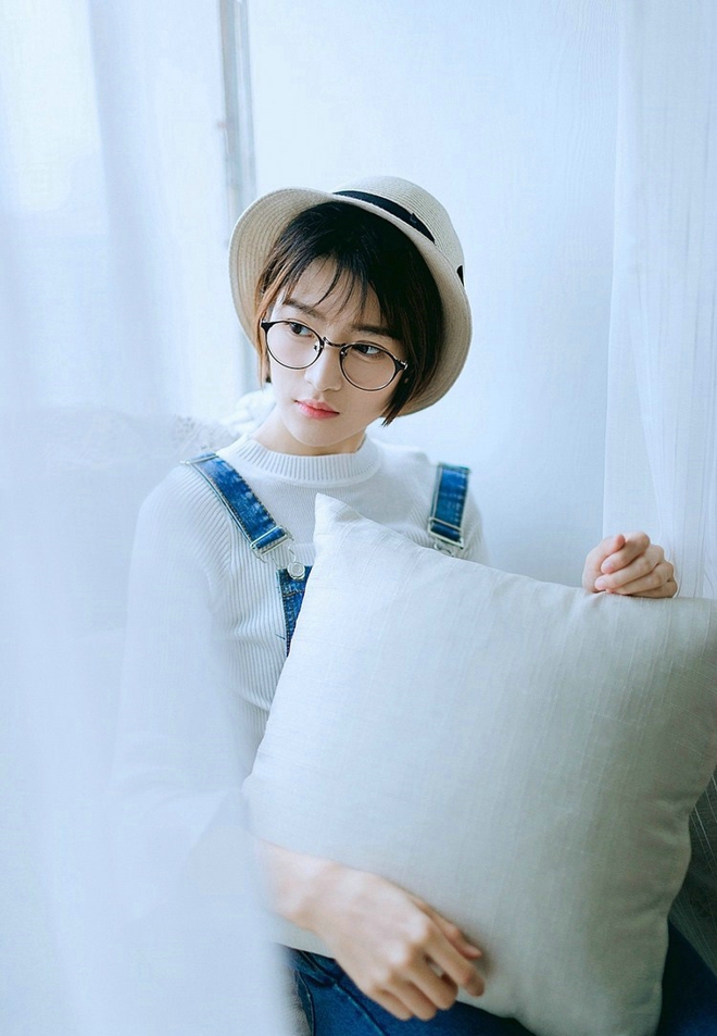 戴眼镜的短发女孩搂抱枕艺术照