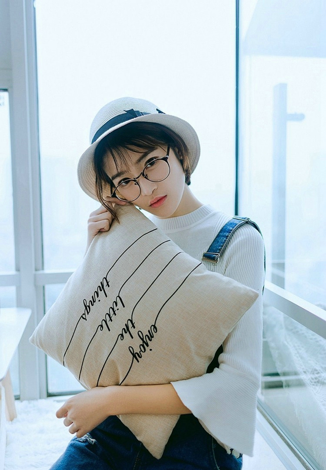戴眼镜的短发女孩搂抱枕艺术照